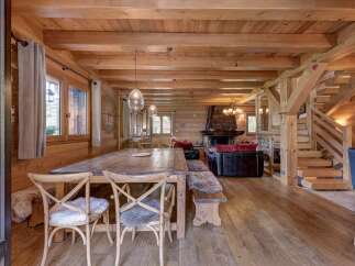 Experience rustic charm in this stunning log cabin living and dining area, featuring a grand wooden dining table perfect for gatherings.
