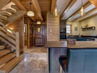 Experience rustic charm in this mountain home featuring a stunning wooden staircase and a cozy entryway.