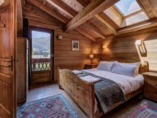 Experience rustic charm in this cozy mountain retreat, featuring a wooden-paneled bedroom with a comfortable bed and a skylight offering natural light.
