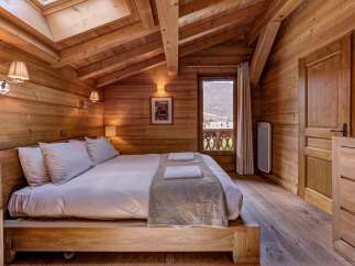 Experience rustic charm and breathtaking mountain views in this cozy wooden cabin bedroom.