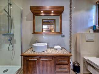 This modern bathroom features a sleek walk-in shower with a chrome showerhead and a spacious vanity with a vessel sink.
