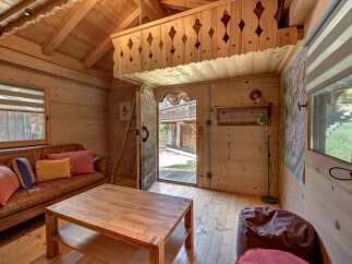 Experience rustic charm in this cozy wooden cabin, featuring a comfortable leather sofa and a rustic wooden coffee table perfect for relaxing evenings.