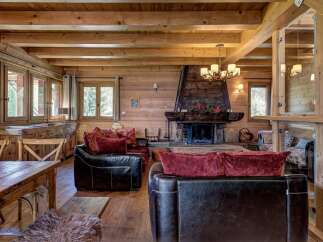 Experience rustic luxury in this charming log cabin living room, featuring a grand stone fireplace as the centerpiece.