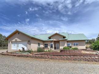 Discover this charming Southwestern-style home featuring a durable metal roof and a welcoming stucco exterior.
