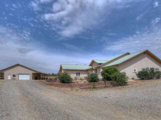 Discover this stunning property featuring a spacious main house with a durable metal roof and a separate large garage/workshop.