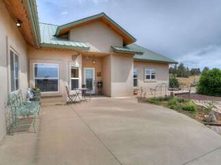 Enjoy outdoor living on this charming stucco home featuring a metal roof and a spacious concrete patio perfect for entertaining.