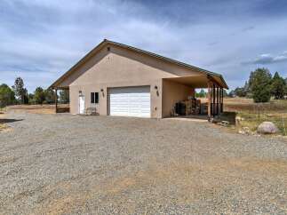 Discover this spacious property featuring a large garage with ample storage and a covered carport area, perfect for vehicles or outdoor projects.