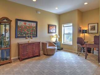 This inviting room features a beautiful floral painting above a wooden cabinet, complemented by a unique display case showcasing a guitar.