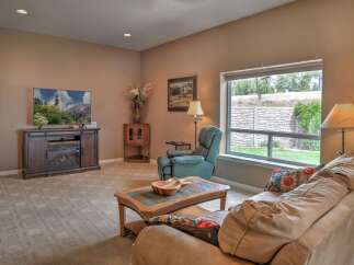 Cozy living room featuring a large flat-screen TV above a fireplace media console, complemented by a comfortable recliner and a plush sofa.