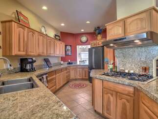 This spacious kitchen boasts beautiful light wood cabinetry and granite countertops, offering ample storage and workspace.