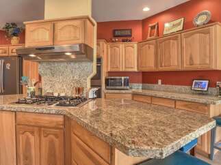 This stunning kitchen boasts beautiful light wood cabinetry and granite countertops, offering a warm and inviting atmosphere.