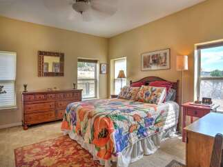 This charming bedroom features a cozy queen-size bed adorned with a vibrant floral quilt and matching throw pillows.