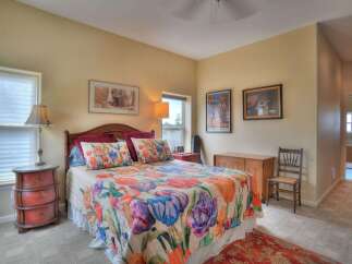 This charming bedroom features a comfortable queen-size bed adorned with a vibrant floral quilt and matching throw pillows.