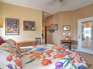 This charming bedroom features a vibrant floral comforter on a comfortable bed, complemented by decorative wall art and a vintage sewing machine table.