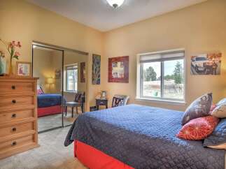 This charming bedroom features a spacious queen-sized bed with a cozy blue quilted comforter and vibrant red bed skirt.