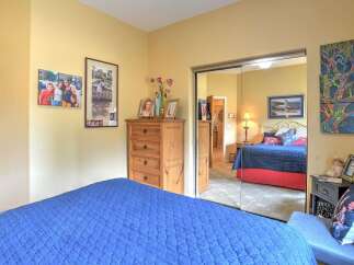 This charming bedroom features a comfortable blue quilted bed and a rustic wooden dresser adorned with personal photos.
