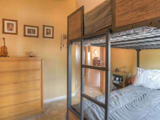 This charming bedroom features a space-saving bunk bed with a rustic wood and metal design, perfect for accommodating guests or children.