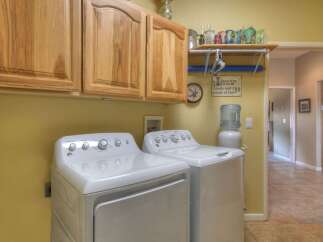 This laundry room features a convenient setup with a washer and dryer, complemented by ample overhead wooden cabinetry for storage.