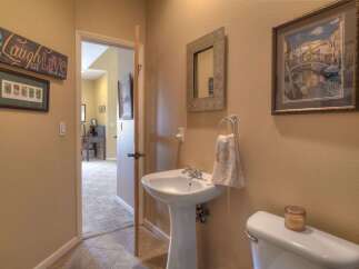 This charming bathroom features a pedestal sink and a toilet, complemented by decorative wall art and a mirror.