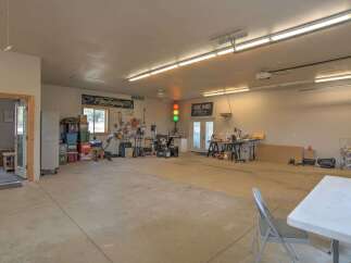 This spacious garage offers ample room for a workshop or storage, featuring multiple workbenches, tools, and organized shelving.