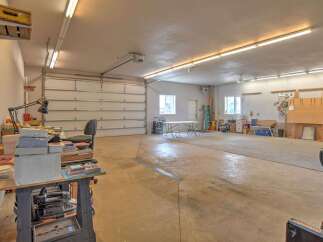 This spacious garage offers ample room for vehicles and storage, featuring a large overhead door for easy access.