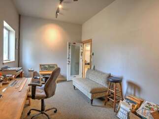 This versatile room features a spacious wooden desk with rulers and art supplies, perfect for creative projects or a home office setup.