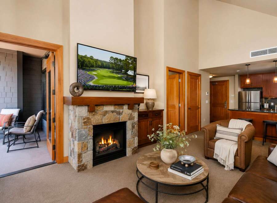 Experience luxury living in this stunning mountain retreat, featuring a cozy stone fireplace and a large flat-screen TV perfect for entertaining.