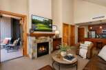 Experience luxury living in this stunning mountain retreat, featuring a cozy stone fireplace and a large flat-screen TV perfect for entertaining.