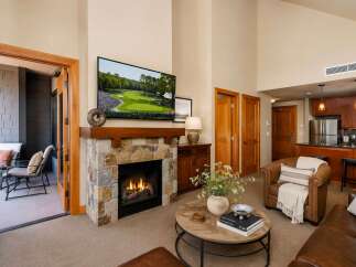 Experience luxury living in this stunning mountain retreat, featuring a cozy stone fireplace and a large flat-screen TV perfect for entertaining.