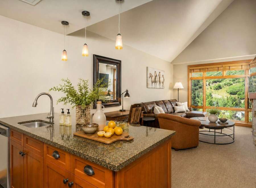 Experience breathtaking mountain views from this stunning living space, featuring a spacious leather sectional and a cozy armchair perfect for relaxation.