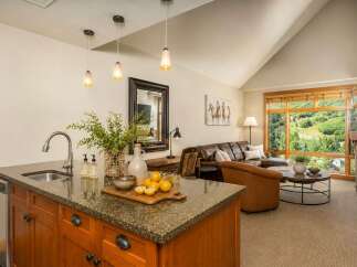Experience breathtaking mountain views from this stunning living space, featuring a spacious leather sectional and a cozy armchair perfect for relaxation.