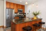 This modern kitchen features warm cherry wood cabinetry and a sleek granite countertop island, perfect for casual dining.