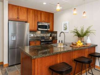 This modern kitchen features warm cherry wood cabinetry and a sleek granite countertop island, perfect for casual dining.