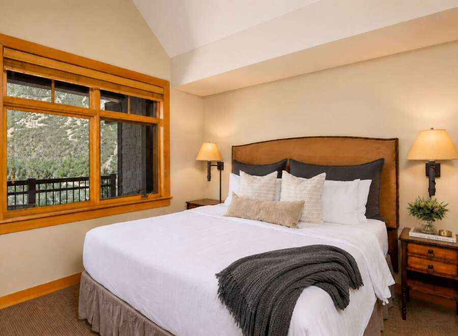 Experience ultimate comfort in this beautifully appointed bedroom, featuring a plush king-size bed adorned with crisp white linens and a cozy charcoal throw.