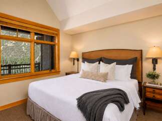 Experience ultimate comfort in this beautifully appointed bedroom, featuring a plush king-size bed adorned with crisp white linens and a cozy charcoal throw.