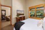 Experience breathtaking mountain views from this serene bedroom, featuring a large window overlooking lush greenery and a private balcony.
