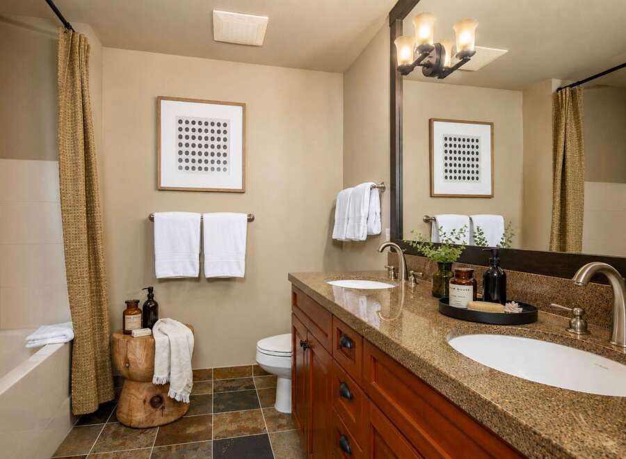 This modern bathroom features a spacious double vanity with granite countertops and elegant wooden cabinetry.