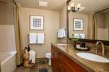 This modern bathroom features a spacious double vanity with granite countertops and elegant wooden cabinetry.