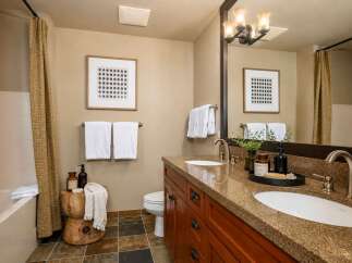 This modern bathroom features a spacious double vanity with granite countertops and elegant wooden cabinetry.