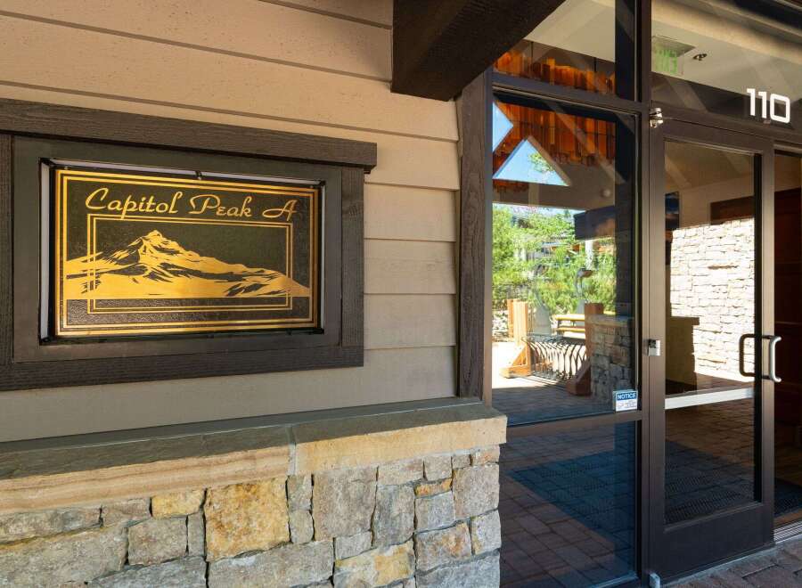 Discover the charm of Capitol Peak A, a property featuring a striking entrance with a decorative sign showcasing a mountain landscape.