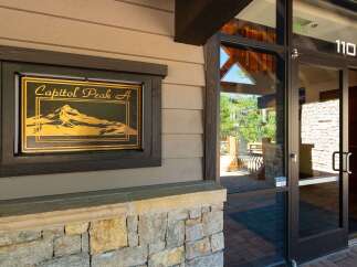 Discover the charm of Capitol Peak A, a property featuring a striking entrance with a decorative sign showcasing a mountain landscape.