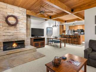 Experience cozy living with this charming living room featuring a stunning stone fireplace and a rustic wood-beamed ceiling.