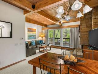 Experience rustic charm in this inviting living and dining area, featuring a cozy sectional sofa adorned with plush blue pillows and a warm wooden coffee table.
