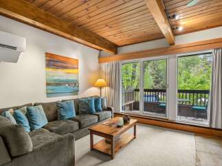 Experience cozy living in this inviting living room, featuring a plush sectional sofa adorned with decorative pillows and a rustic wooden coffee table.