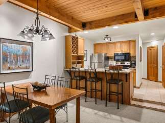 This charming dining area and kitchen features a rustic wooden dining table with seating for four, complemented by a stylish chandelier.