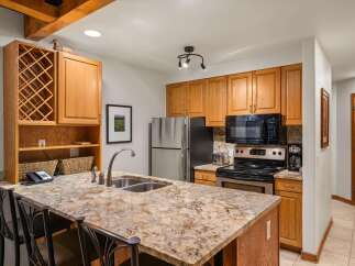 This charming kitchen features warm oak cabinetry and a spacious granite island with a double sink, perfect for meal preparation and casual dining.