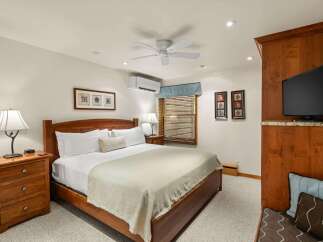 Experience ultimate comfort in this beautifully appointed bedroom, featuring a plush king-size bed with crisp white linens and a cozy throw blanket.