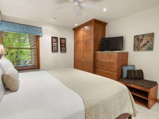 Experience comfort and style in this inviting bedroom, featuring a plush bed adorned with crisp white linens and a cozy throw blanket.