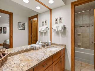 This bathroom features a spacious vanity with a granite countertop and ample storage.