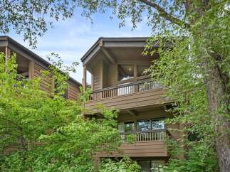 Nestled amidst lush greenery, this charming property features a warm, wood-paneled exterior and multiple balconies offering serene views.